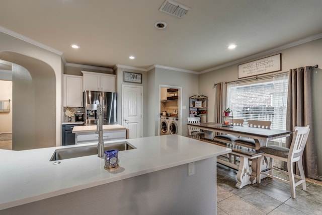 kitchen with stainless steel refrigerator with ice dispenser, sink, backsplash, white cabinets, and washer and clothes dryer