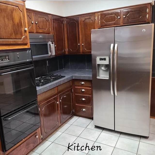 kitchen featuring light tile patterned flooring, appliances with stainless steel finishes, and decorative backsplash