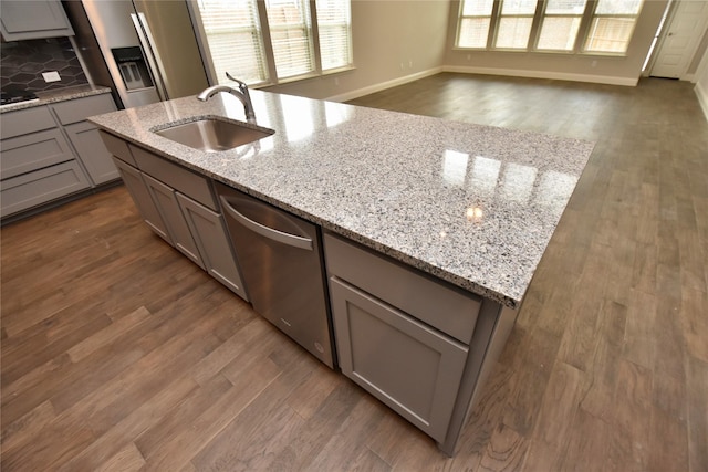 kitchen featuring sink, gray cabinets, light stone countertops, dark hardwood / wood-style flooring, and stainless steel dishwasher