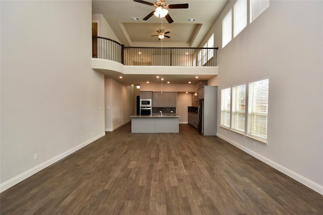 unfurnished living room featuring ceiling fan and dark hardwood / wood-style flooring