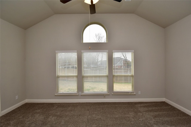 unfurnished room featuring lofted ceiling, dark carpet, and plenty of natural light