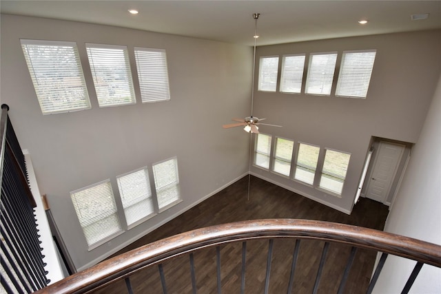 stairs featuring a towering ceiling, wood-type flooring, and ceiling fan