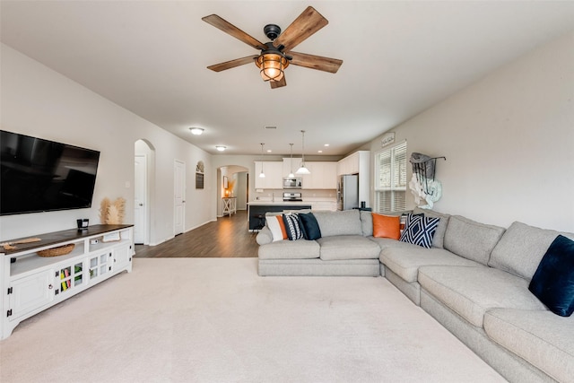 living room with arched walkways, wood finished floors, recessed lighting, and a ceiling fan