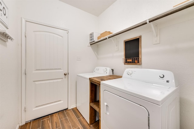 clothes washing area featuring washing machine and clothes dryer, laundry area, and wood finish floors