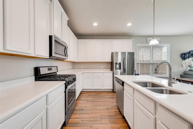 kitchen featuring white cabinetry, a sink, wood finish floors, and appliances with stainless steel finishes