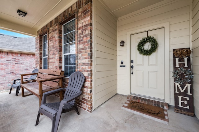 entrance to property with a porch and brick siding