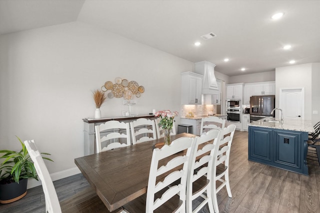 dining space with sink, vaulted ceiling, and light hardwood / wood-style floors