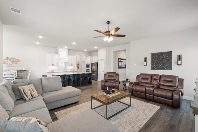 living room featuring dark wood-type flooring, sink, and ceiling fan