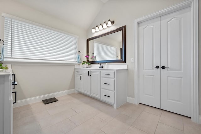 bathroom featuring tile patterned flooring, vaulted ceiling, and vanity