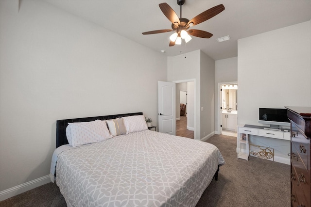 bedroom featuring dark carpet, vaulted ceiling, ensuite bath, and ceiling fan