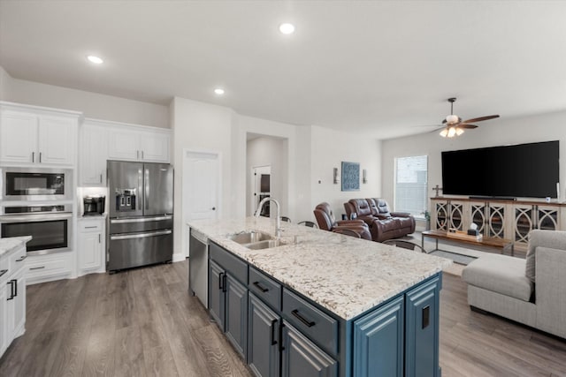 kitchen featuring sink, hardwood / wood-style floors, stainless steel appliances, an island with sink, and white cabinets