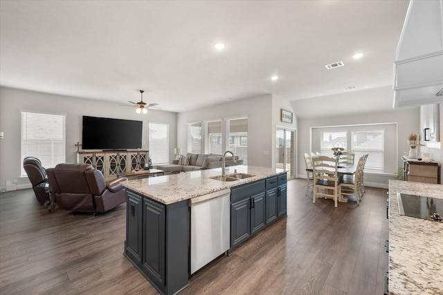 kitchen featuring dishwasher, sink, dark hardwood / wood-style flooring, a kitchen island with sink, and light stone counters