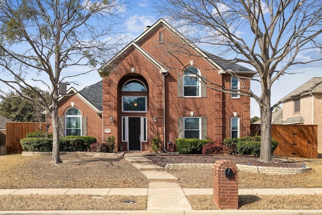 traditional home featuring fence and brick siding