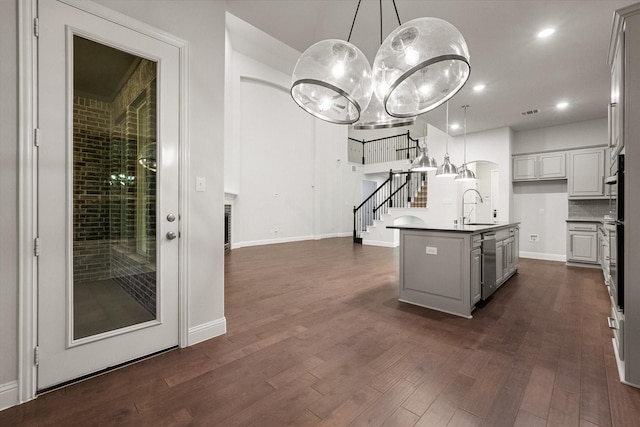 kitchen featuring pendant lighting, sink, appliances with stainless steel finishes, a kitchen island with sink, and dark hardwood / wood-style flooring