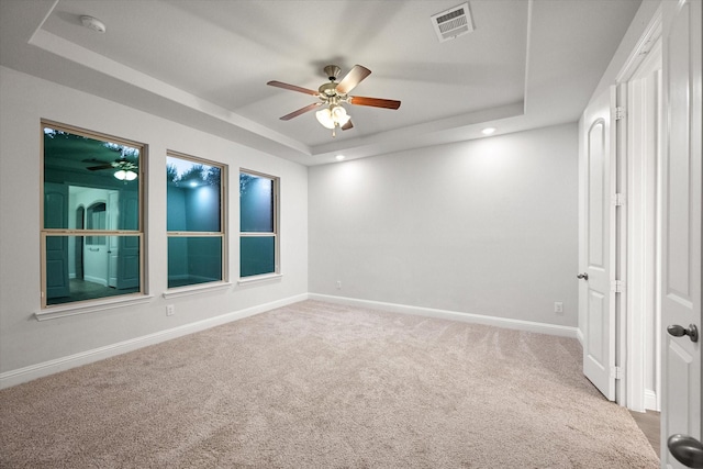 carpeted empty room featuring ceiling fan and a tray ceiling