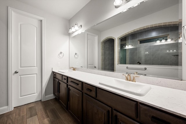 bathroom featuring hardwood / wood-style flooring, tiled shower, and vanity