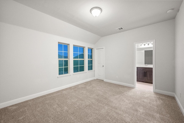 carpeted spare room featuring vaulted ceiling and sink