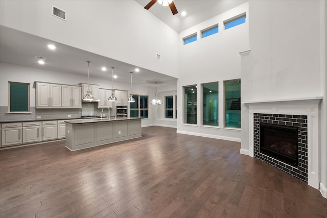 unfurnished living room featuring ceiling fan, sink, a fireplace, and dark hardwood / wood-style floors