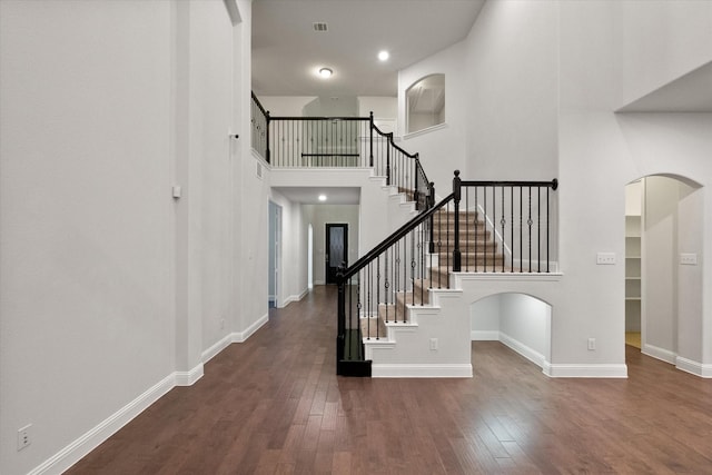 stairway featuring a high ceiling and wood-type flooring