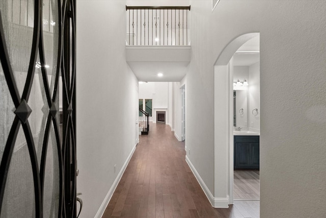 hall featuring sink, a towering ceiling, and dark wood-type flooring