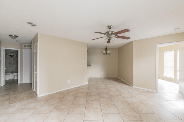 tiled empty room featuring ceiling fan with notable chandelier