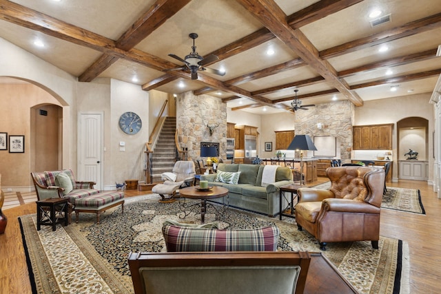 living area with ceiling fan, arched walkways, and coffered ceiling