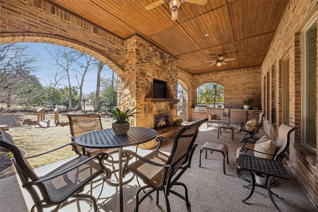 view of patio featuring a ceiling fan and an outdoor stone fireplace