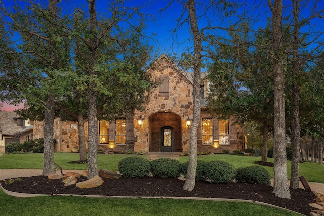 tudor home with stone siding, brick siding, and a front yard