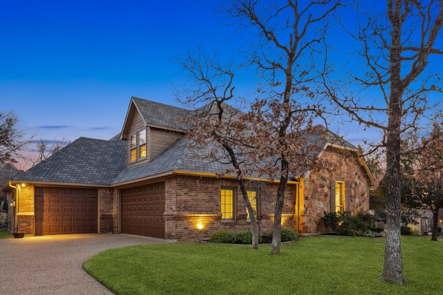 view of front facade featuring a garage, a yard, brick siding, and driveway