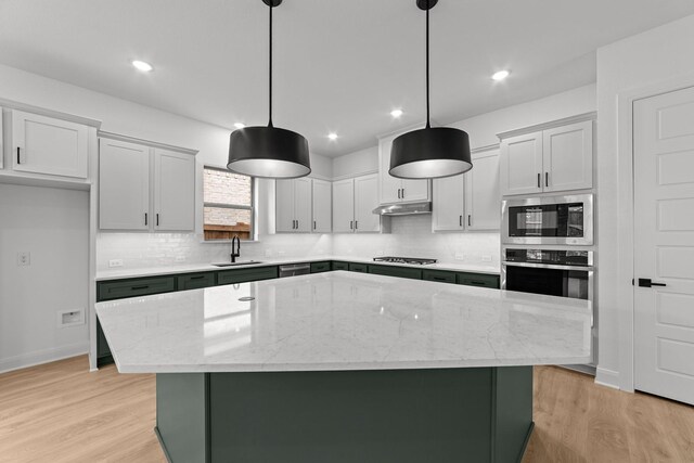 602 Lundy Ln, Mansfield, TX 76063 - kitchen featuring stainless steel appliances, a sink, backsplash, a kitchen island, and light wood-type flooring