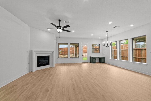 602 Lundy Ln, Mansfield, TX 76063 - unfurnished living room featuring a glass covered fireplace, baseboards, light wood-type flooring, recessed lighting, and a chandelier
