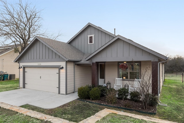 view of front of house with central AC unit, a garage, a front lawn, and covered porch