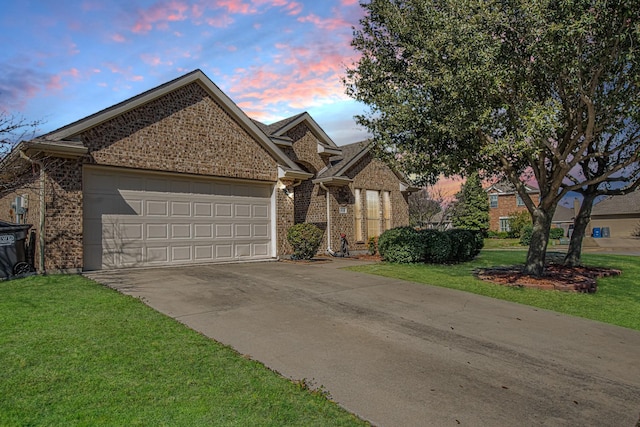 view of front of home with brick siding, a lawn, driveway, and an attached garage