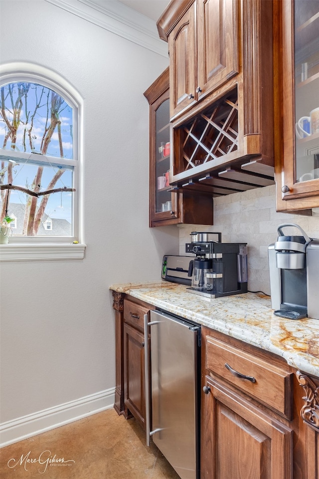 bar featuring tasteful backsplash, light stone counters, ornamental molding, and fridge