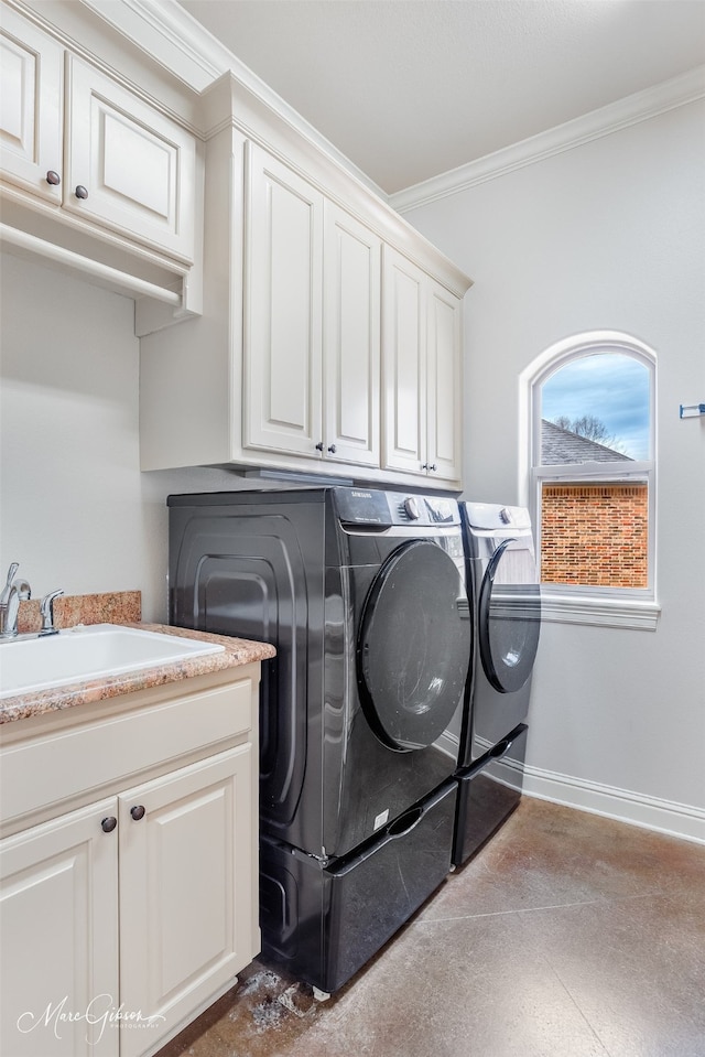 washroom with cabinets, washing machine and clothes dryer, crown molding, and sink