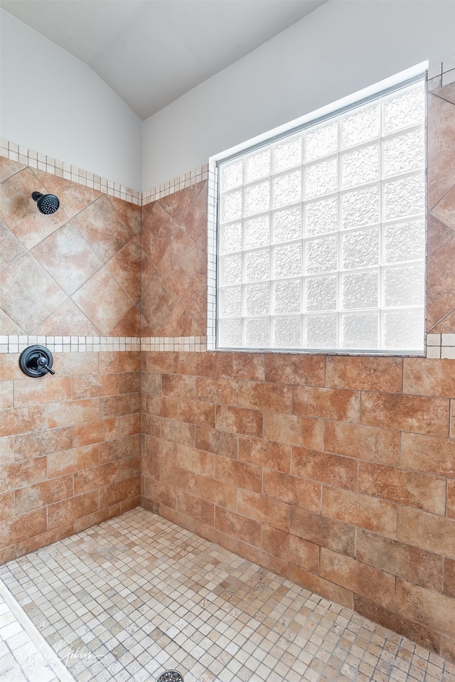 bathroom with lofted ceiling and a tile shower