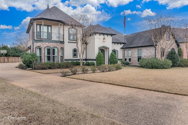 french country inspired facade featuring a front lawn and a balcony