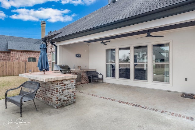 view of patio / terrace with grilling area, an outdoor bar, ceiling fan, and exterior kitchen