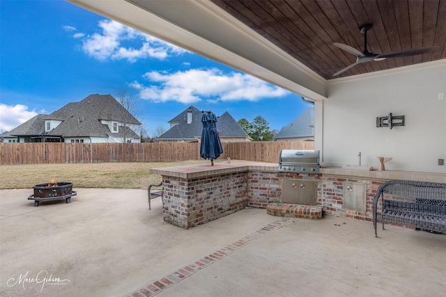 view of patio / terrace featuring a grill, a wet bar, exterior kitchen, ceiling fan, and an outdoor fire pit