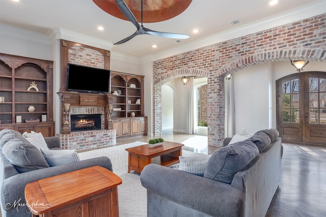 living room featuring french doors, crown molding, a brick fireplace, ceiling fan, and brick wall