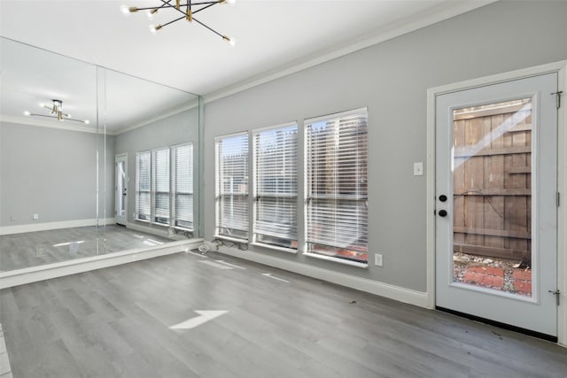 empty room featuring wood-type flooring, an inviting chandelier, and crown molding