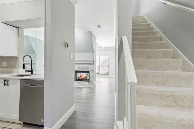 stairway with hardwood / wood-style floors, a tiled fireplace, and sink