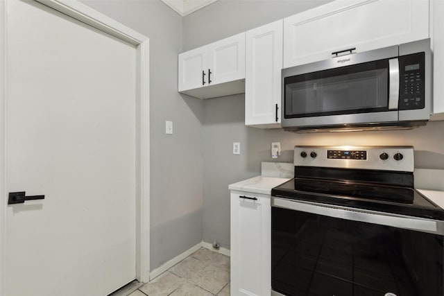 kitchen with appliances with stainless steel finishes, light tile patterned floors, and white cabinets