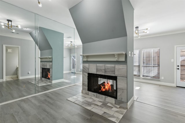 living room with a tiled fireplace, hardwood / wood-style flooring, and crown molding