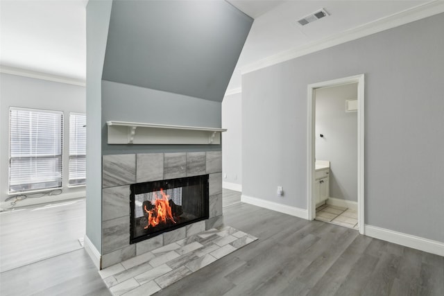 unfurnished living room featuring crown molding, wood-type flooring, and a tiled fireplace