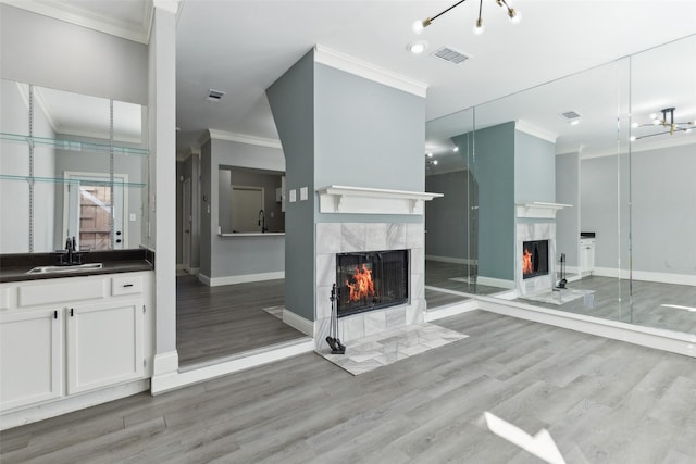 bathroom featuring hardwood / wood-style flooring, vanity, crown molding, and a high end fireplace