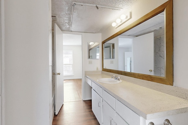 bathroom with visible vents, vanity, a textured ceiling, and wood finished floors