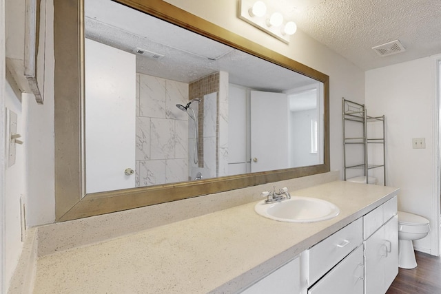 full bath featuring visible vents, toilet, vanity, and a textured ceiling