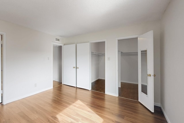 unfurnished bedroom featuring visible vents, baseboards, and wood finished floors