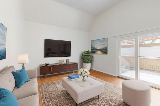 living room featuring light wood-style floors, lofted ceiling, and baseboards